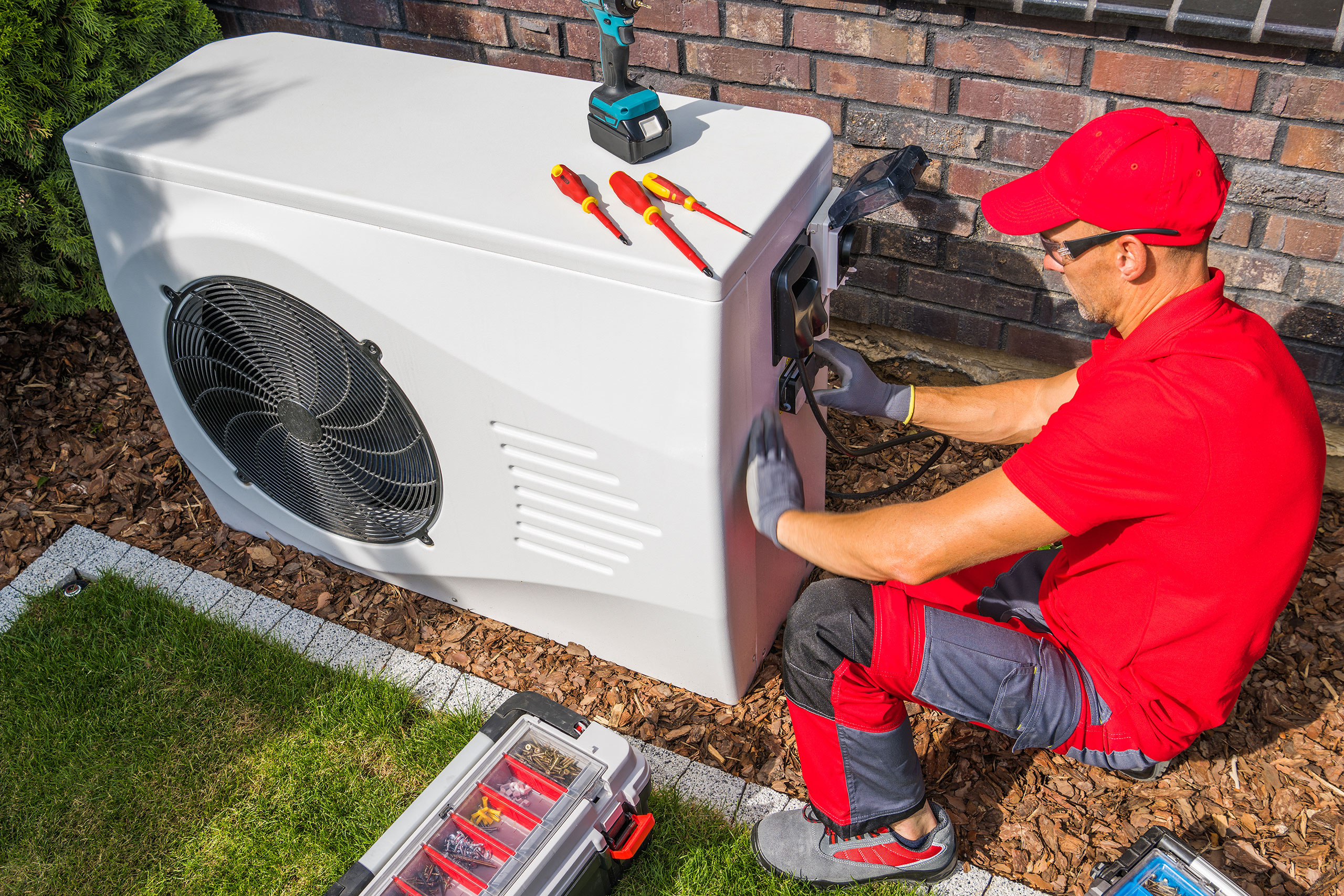 Handwerker installieren eine Wärmepumpe an einem Wohnhaus.